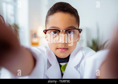 Cute dark-eyed boy making photo in white jacket of father Stock Photo