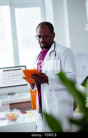 Doctor using tablet while searching for some information Stock Photo