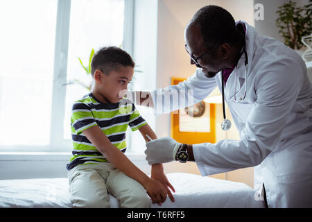 Pleasant pediatrician making injection for cute little boy Stock Photo