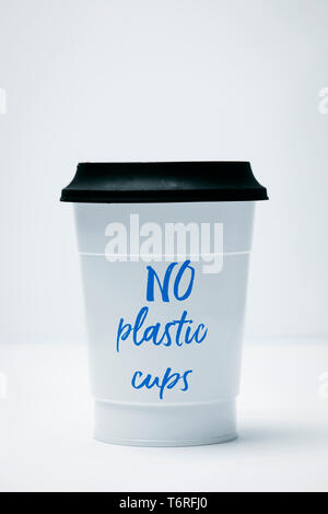 closeup of a white plastic cup, with text no plastic cups written in it, covered with a black lid, on a white background Stock Photo