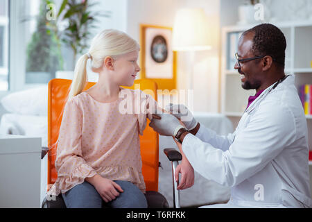 Pediatrician smiling while making injection for schoolgirl Stock Photo