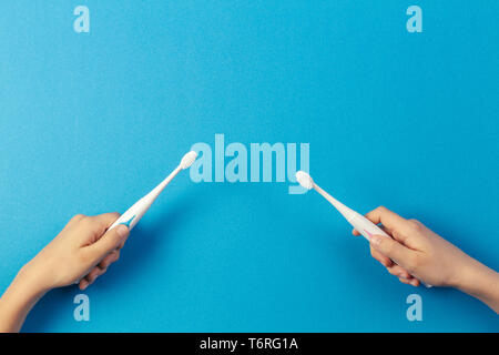 Kid hands with electric toothbrushes on blue background Stock Photo