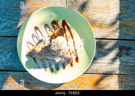 Delicious cake on white plate and natural wooden table, overhead shot, outdoor Stock Photo