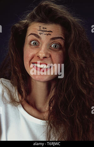Portrait of young woman overcoming mental health problems. Tattoo on the forehead I'm desperate-optimistic. Concept of psycological trouble, treatment, rehabilitation, return to healthy lifestyle. Stock Photo