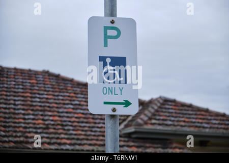 Handicapped/Disabled parking only sign outside a house with roof and sky visible in Melbourne, Australia Stock Photo