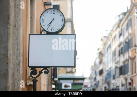 Street clock and empty rectangular blank sign on the street in the city - Image Stock Photo