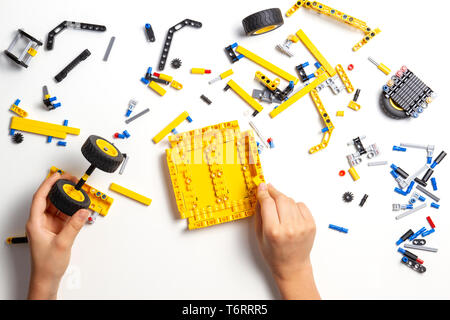 Kid hands making new robot car on white table Stock Photo