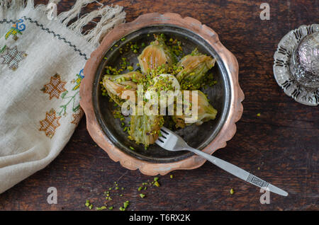 Mussel shaped special Turkish baklava with pistachio in the copper plate, top view. .Conceptual of Islamic Feasts. Stock Photo