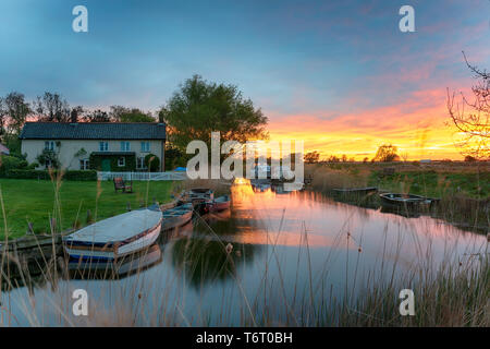 Fiery sunset over boats moored on the river at West Somerton a picturesque village on the Norfolk Broads Stock Photo