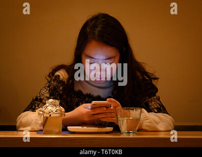 Woman checking her cell phone in a bar in Shanghai, China, French consession Stock Photo