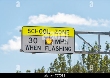 Public School Zone sign on road with 30 miles per hour when flashing text in Naples, Florida during day Stock Photo