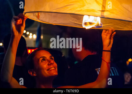 Chiang Mai, Thailand - Nov 2015: Group of friends lightning up a lantern to release it during Loy Krathong festival in Chiang Mai Stock Photo