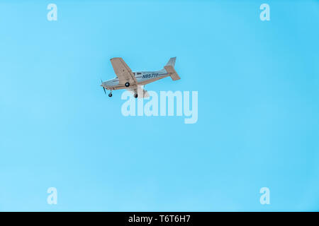 Naples, USA - April 30, 2018: Private charter plane flying isolated in vibrant blue turquoise sky luxury jet airplane in Florida Stock Photo