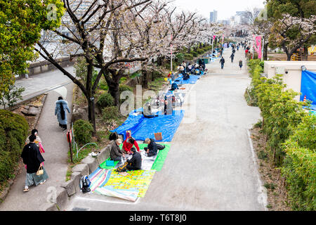 Tokyo, Japan - March 30, 2019: Sumida Asakusa district area with many people sitting on picnic blankets looking at cherry blossom in downtown on cloud Stock Photo