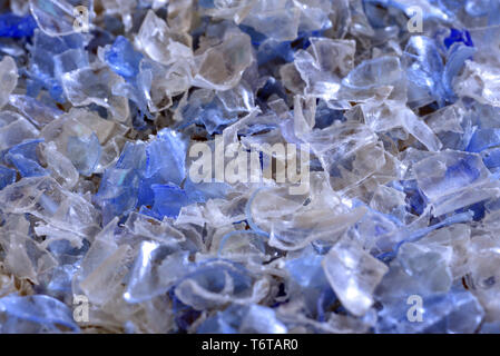 Flakes of crushed plastic bottles as raw material for further processing. Stock Photo