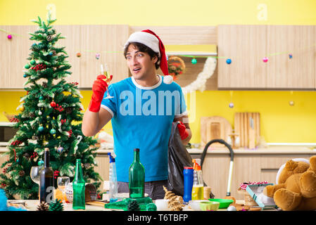 Young man cleaning kitchen after Christmas party Stock Photo