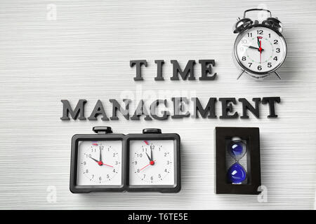 Composition with different clocks and phrase 'Time management' on table Stock Photo
