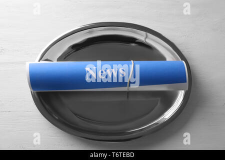 Roll of papers with word NEWS on metal tray Stock Photo