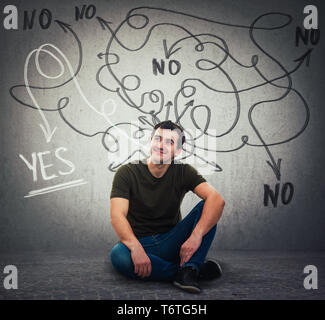 Smart guy sitting on the floor looking away dreaming, having new ideas, finding correct answer to questions as curves arrows escape from head leading  Stock Photo