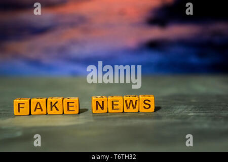Fake news on wooden blocks. Cross processed image with bokeh background Stock Photo
