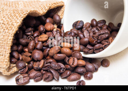 roasted coffee beans with raw textile and white porcelain coffee cup Stock Photo