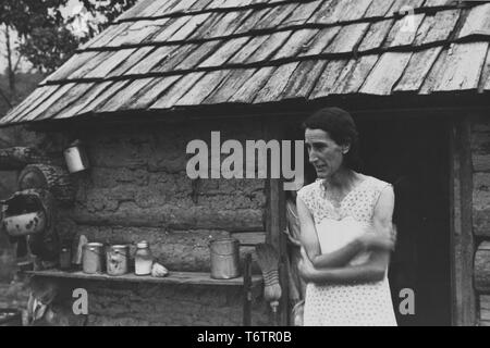 Photograph of a mid-age woman, Ozark Mountaineer, standing outside her house in Boone County, Arkansas, 1935. From the New York Public Library. () Stock Photo