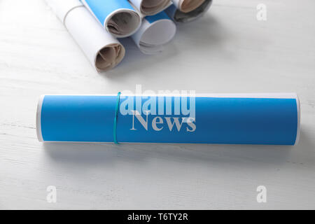 Roll of papers with word NEWS on wooden table Stock Photo