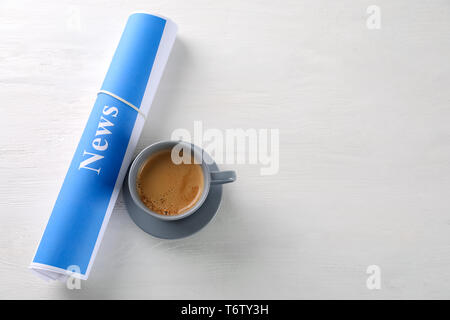 Roll of papers with word NEWS and cup of coffee on wooden table Stock Photo