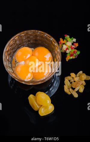 Bright yellow egg yolks in a glass bowl on black background. Ingredients for cooking delicious dishes. Stock Photo