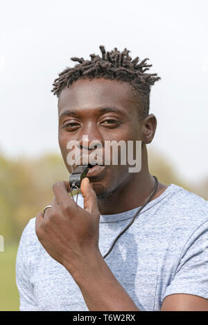England, UK, circa 2019. Portrait of a referee or coach about to blow a black whistle. Stock Photo