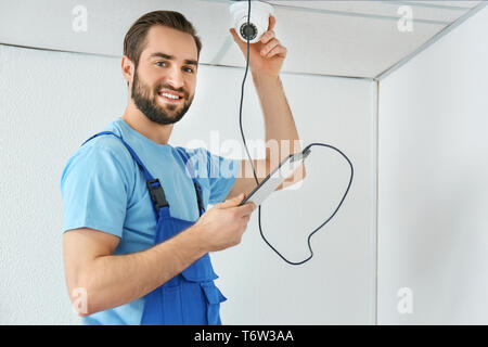 Electrician inspecting surveillance camera Stock Photo