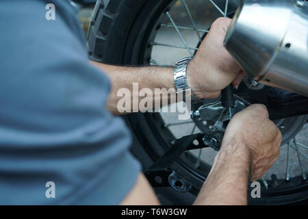 close up technician worker hand, fixed motocycle wheel at the outside of garage. Stock Photo