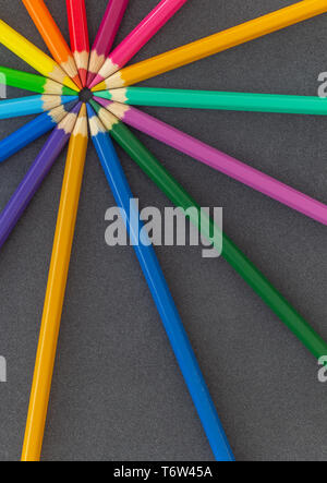 Colored pencils in circle close together on dark background Stock Photo