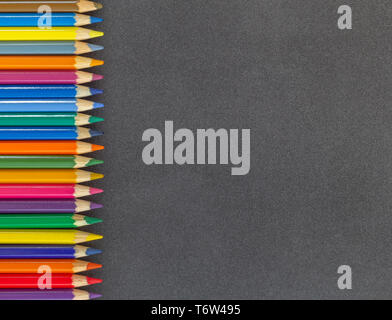 Line of colored pencils left side dark background top view Stock Photo