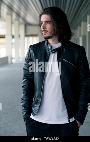Half length portrait of handsome bearded man dressed in fashionable clothes standing on street against while wall background with area for advertising content. Handsome hipster guy posing on copy space Stock Photo