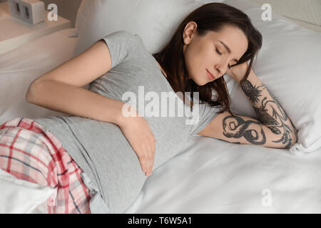 Beautiful pregnant woman lying on bed in morning Stock Photo