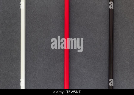 White, red and black colored pecnils line on dark backgroung top view Stock Photo