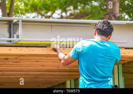 Asian worker measure the steel waterdrain structure of the roof top for home improvement and development. Stock Photo