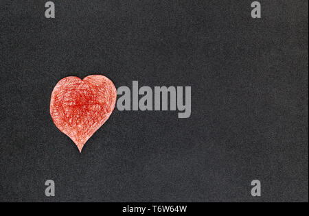 A paper-cut heart painted red with a color pencil lying on a black background top view Stock Photo