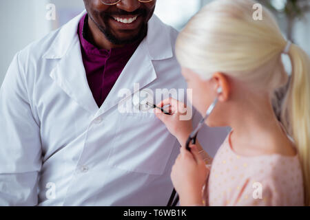 Blonde patient using stethoscope playing with doctor Stock Photo