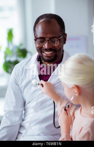 Dark-skinned pediatrician feeling happy spending day with daughter Stock Photo