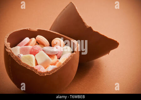 traditional Easter chocolate egg broken in half and filled with candies Stock Photo