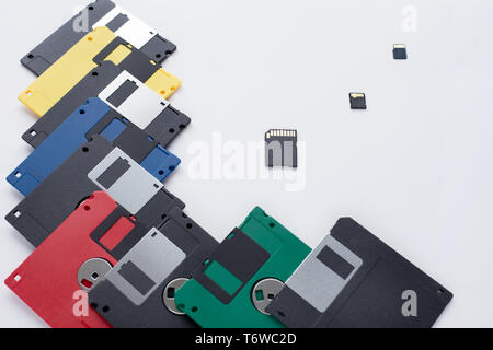 The evolution of digital data storage device. Floppy disks vs small memory cards. Isolated on a white background. Modern and retro technology. Stock Photo