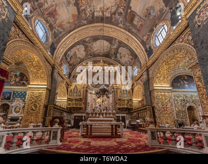 The sumptuous Nave of St John's Co-Cathedral in Valletta with Giuseppe Mazzuoli's main altar marble group of the Baptism of Christ Stock Photo