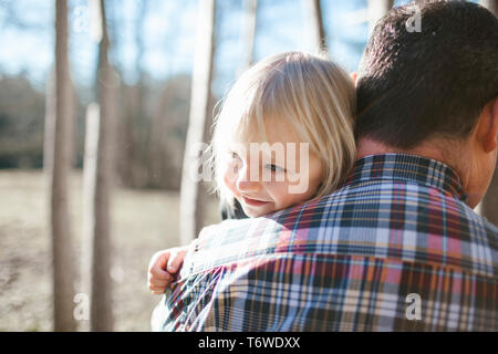 Father holding daughter, looking over his shoulder Stock Photo