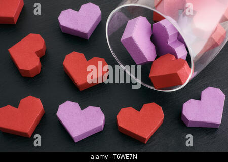 Paper origami hearts spilling out of a glass. Concept image. Close up. Stock Photo