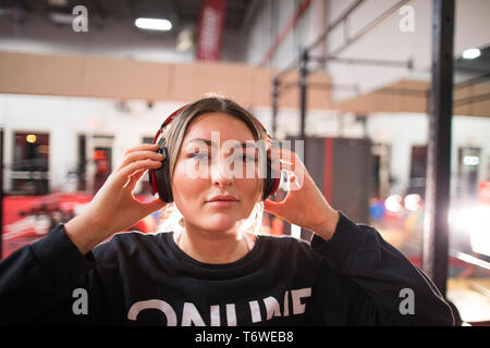 Attractive woman puts headphones on while at the gym Stock Photo