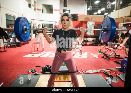 Woman weight lifting with barbell in gym Stock Photo