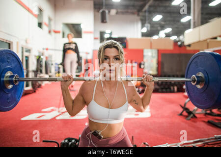 Woman lifting barbell in gymnasium