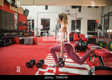 Side view of Attractive Woman doing kettlebell exercises at gym Stock Photo